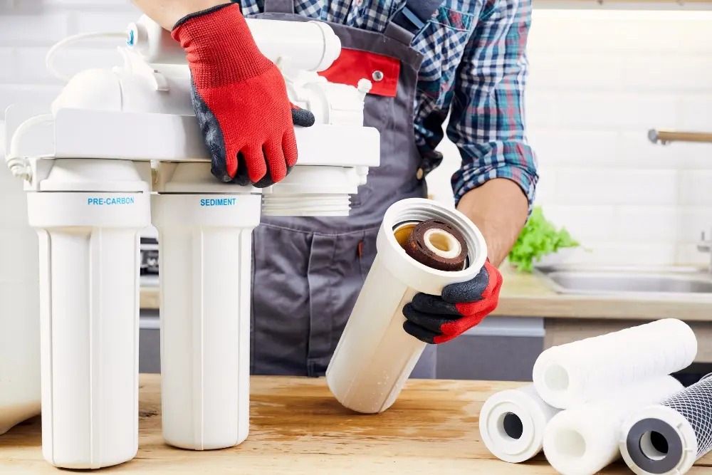 person changing cartridges in a water filtration system